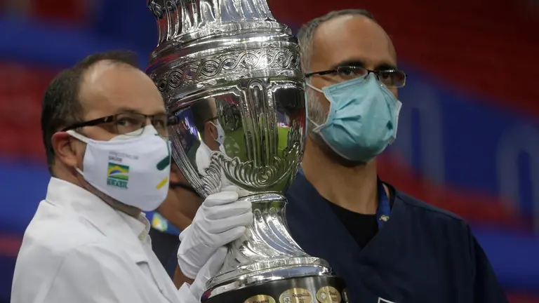 Trabajadores sanitarios llevan el trofeo de la Copa América, durante el acto inaugural del certamen. EFE