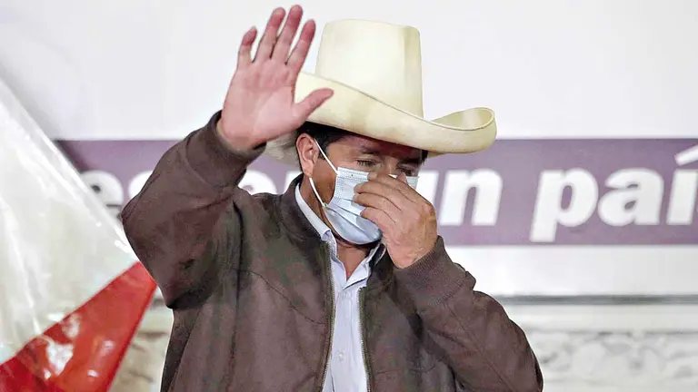 El candidato presidencial peruano Pedro Castillo saluda mientras acomoda su tapabocas durante una rueda de prensa en Lima.  EFE