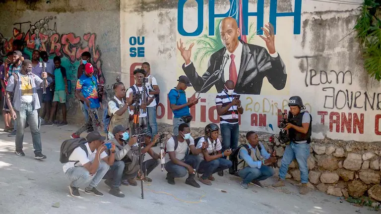 Un grupo de personas se reúnen en la calle junto a un mural del asesinado presidente Jovenel Moise hoy, en Puerto Príncipe (Haití). EFE