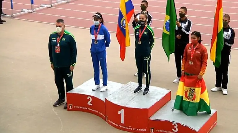 La atleta nacional muestra la bandera del pa&iacute;s, junto a las ganadoras de la prueba. Captura de video