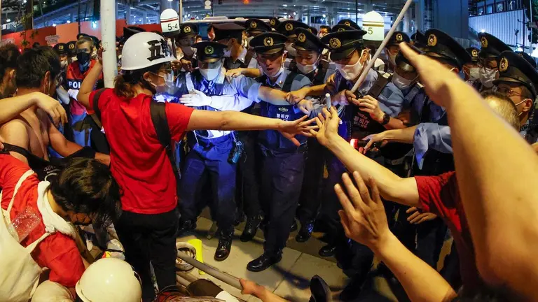 Manifestantes se enfrentan con las fuerzas de seguridad durante una protesta contra la celebración de los Juegos Olímpicos de Tokio 2020, hoy viernes frente al Estadio Olímpico, durante la ceremonia de inauguración. EFE