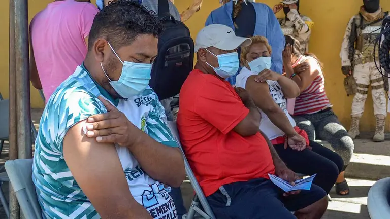 Varias personas migrantes reposan tras ser vacunados contra la Covid-19 hoy, en Tijuana, estado de Baja California (México). EFE