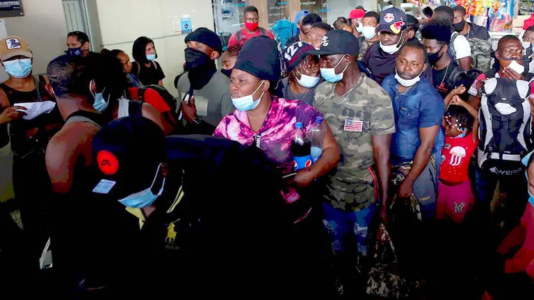 Migrantes haitianos esperan hoy para abordar un bus, en Cali (Colombia). EFE