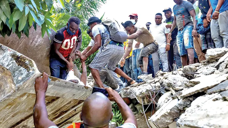 Un grupo de personas  sacan el cuerpo sin vida del senador Jean Gabriel Fortuné tras el terremoto.       EFE