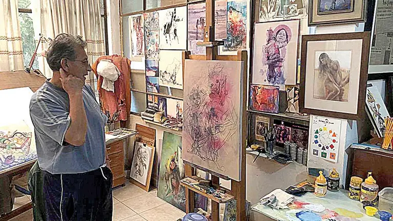 El pintor Leonardo Aliaga en su taller junto a sus cuadros.  OPINIÓN