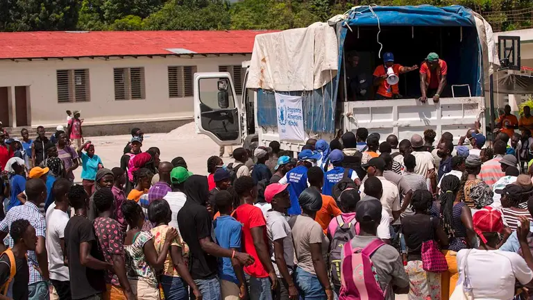 Personas esperan para recibir comida que repartiría el Programa Mundial de Alimentos, este viernes en Camp Perrin (Haití). EFE