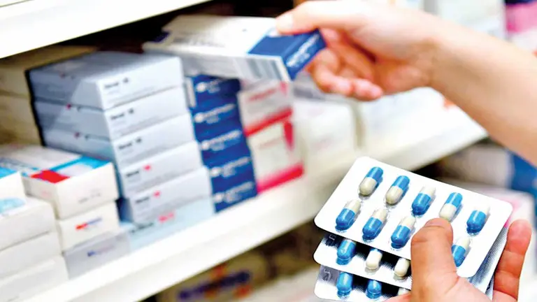 Una farmacéutica acomoda medicamentos en un estante. CONTACTO ECONÓMICO