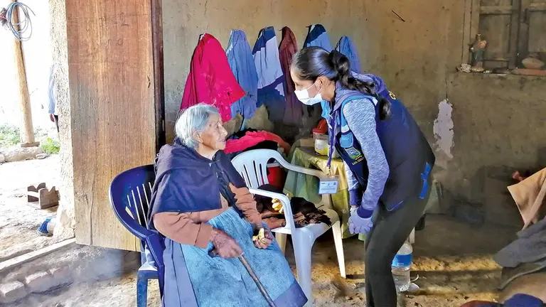 Una adulta mayor es asistida por una funcionaria de la Alcaldía. ALCALDÍA COLCAPIRHUA