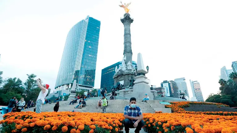 Un hombre se toma una fotografía con las flores de cempasúchil colocadas en el monumento del Angel de la Independencia para conmemorar el día de muertos, hoy en Ciudad de México. EFE