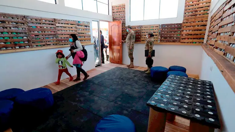 Varias personas ingresan a una "ecoaula", construida con ecoladrillos hechos de botellas PET rellenas con residuos pl&aacute;sticos, en la Unidad Educativa Willcacota, en el municipio de Achocalla, colindante con La Paz y El Alto. EFE