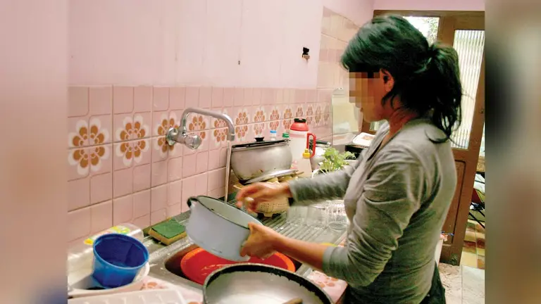 Una mujer lava la vajilla en una casa. ARCHIVO