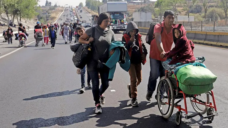 Una familia de migrantes camina por el municipio de San Martín Texmelucan, en la autopista Puebla-México. EFE