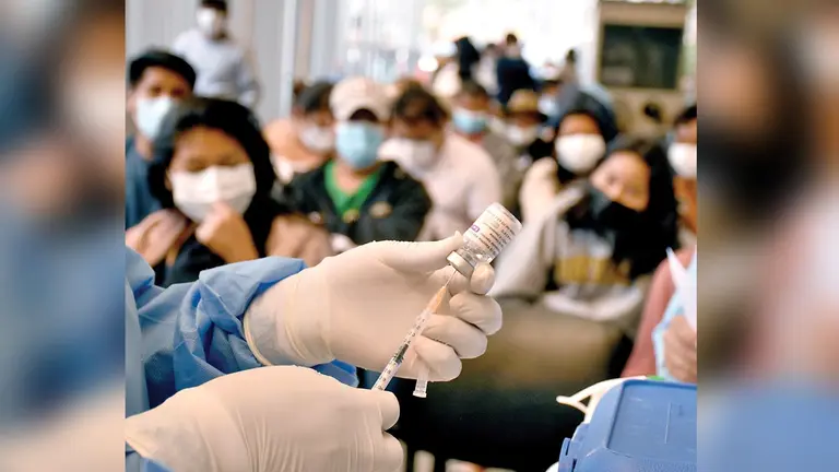 Una enfermera alista una dosis contra el coronavirus, mientras varias personas aguardan su turno. DICO SOLÍS