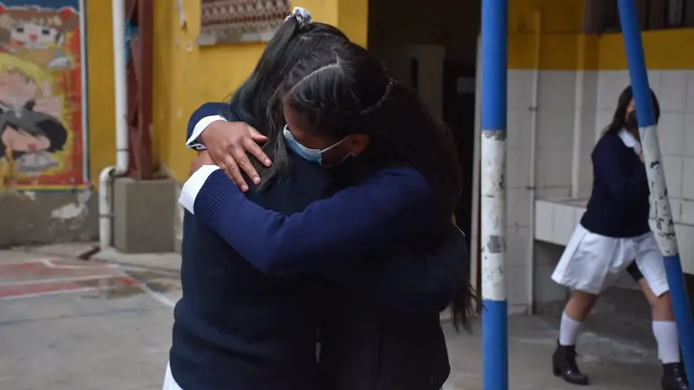 Dos estudiantes se abrazan en el regreso de las clases presenciales en La Paz. APG