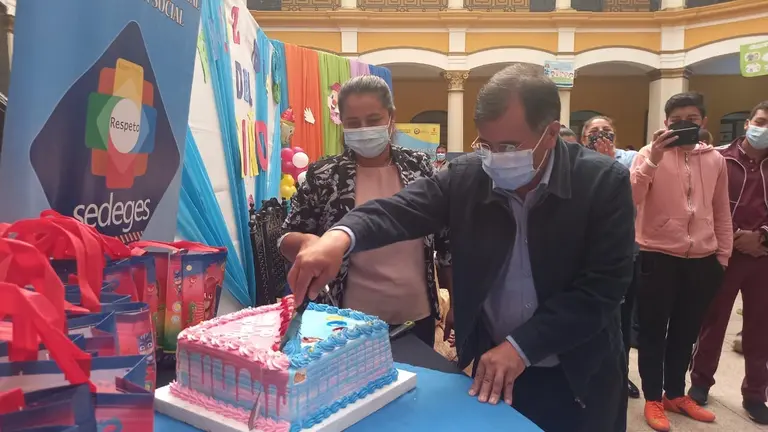 El gobernador de Cochabamba, Humberto Sánchez, parte la torta en la festividad por el Día del Niño. GADC