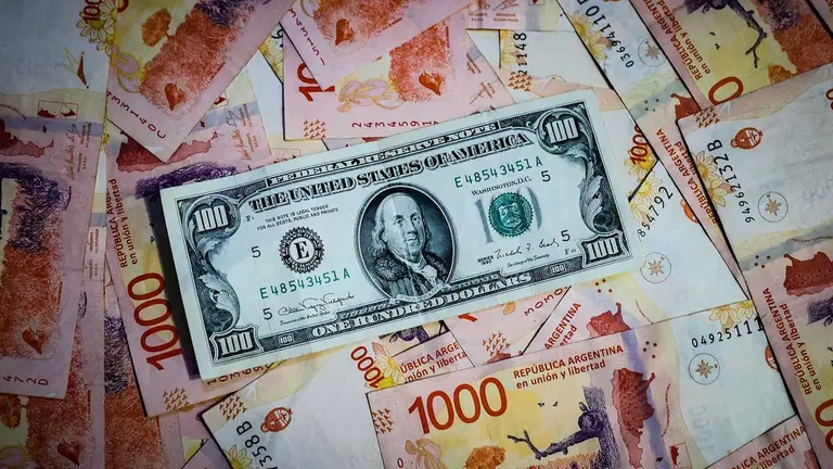 Fotografía de archivo de comparativa de billetes de pesos argentinos con un billete de 100 dólares estadounidenses. EFE