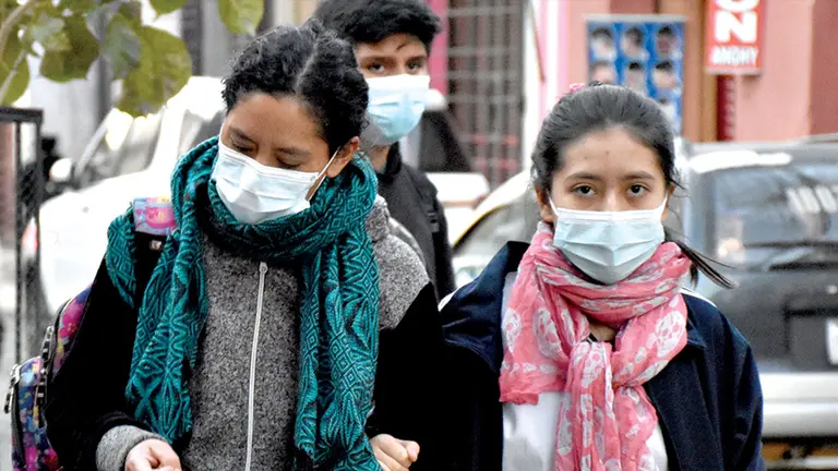 Dos mujeres abrigadas y con barbijo por el fr&iacute;o en Cochabamba.
