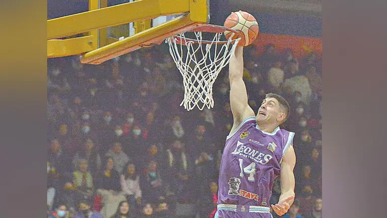 Un jugador de Leones clava la pelota en el aro. APG