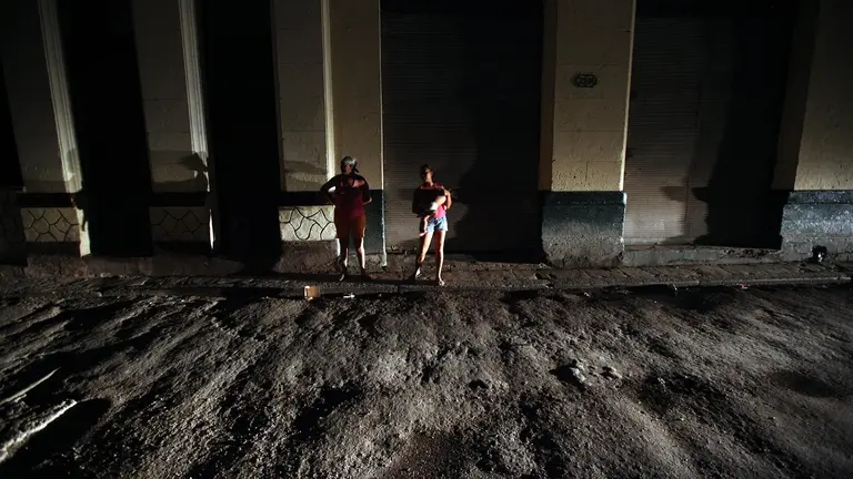 Un par de mujeres al conversar en medio de una calle sin iluminaci&oacute;n.     EFE
