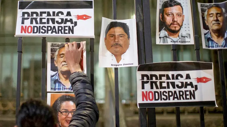 Fotografía de archivo de un periodista que pega una fotografía, durante una protesta el 14 de febrero de 2022, al exterior de la Secretaria de Gobernación (SG), en la Ciudad de México (México). EFE