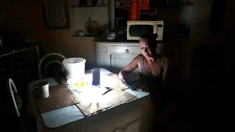 Una mujer revisa unas notas con la luz de una l&aacute;mpara durante un apag&oacute;n, el 18 de agosto de 2022, en La Habana (Cuba). EFE