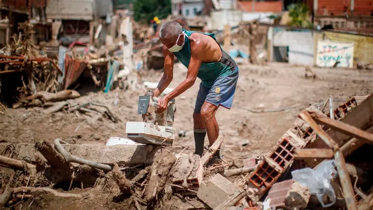 Personas buscan objetos para rescatar entre los escombros tras derrumbes provocados por las fuertes lluvias en Las Tejer&iacute;as (Venezuela). EFE