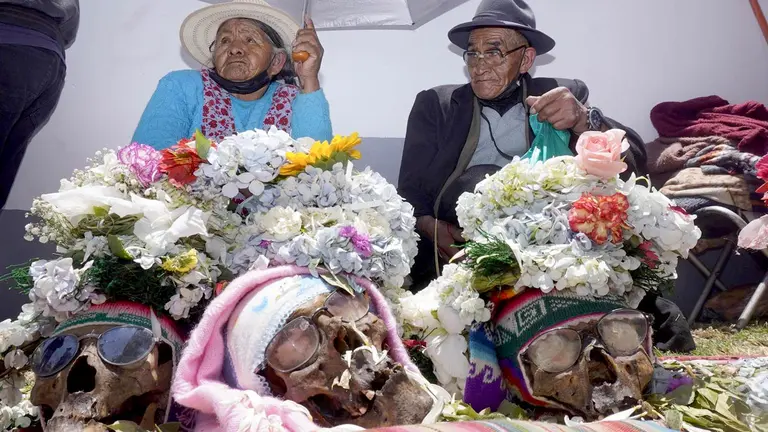 Personas rinden culto a las denominadas "&ntilde;atitas" o cr&aacute;neos humanos, con un cigarrillo y flores hoy, en un cementerio en La Paz. EFE