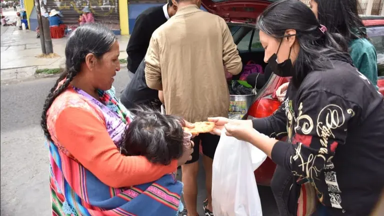 Una mujer con su hijo  reciben api con bu&ntilde;uelo y algunos presentes por Navidad, en Cochabamba. NO&Eacute; PORTUGAL