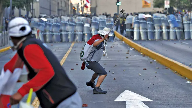 Manifestantes y polic&iacute;as se enfrentan durante una marcha antigubernamental, en Lima. EFE