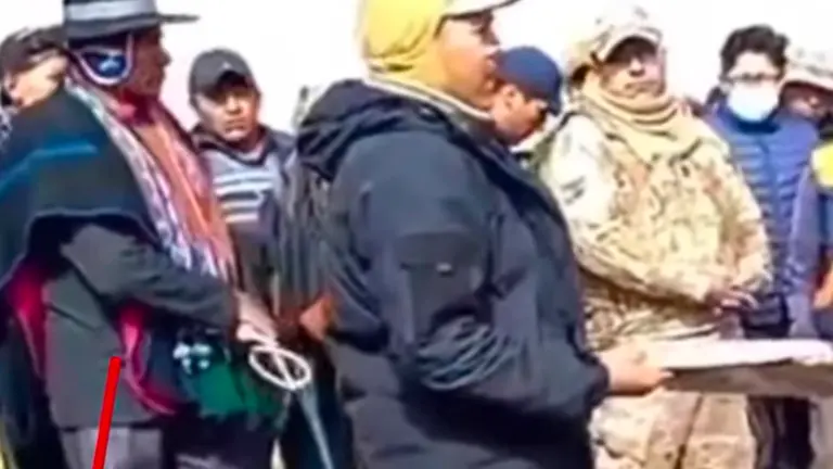 Técnicos aduaneros leyendo un acta de acuerdo, rodeados de comunarios de la localidad de Calamarca en La Paz, para evitar el comiso de vehículos indocumentados. URGENTE.BO