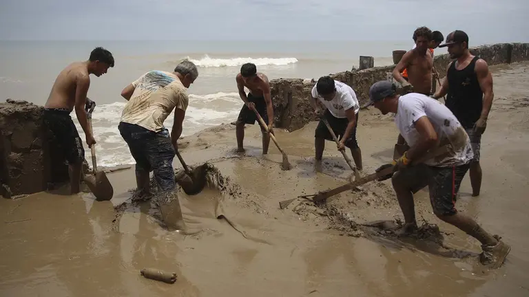 Fotograf&iacute;a de archivo, tomada el pasado 15 de marzo, en la que se registr&oacute; a un grupo de personas al remover lodo de una calle anegada por las lluvias, en el balneario de Punta Hermosa, al sur de Lima (Per&uacute;)./ EFE