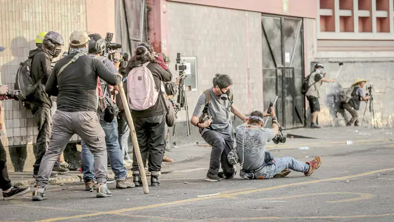 Fotógrafos y miembros de la prensa se protegen mientras cubren las confrontaciones entre Policía y manifestantes en el Parque Universitario, durante la llamada "toma de Lima" en Lima./ EFE.