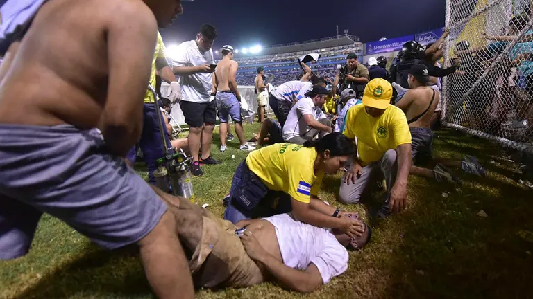 Fan&aacute;ticos auxilian a personas durante una estampida en el Estadio Cuscatl&aacute;&aacute;n previo a un partido de la Liga Mayor, hoy en San Salvador (El Salvador)./ EFE