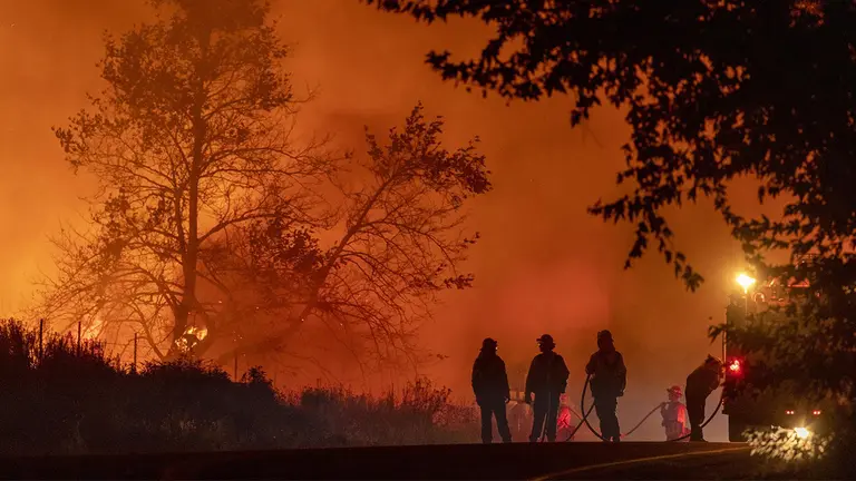 Vista de un incendio forestal atendido por un grupo de bomberos, en una fotograf&iacute;a de archivo./ EFE