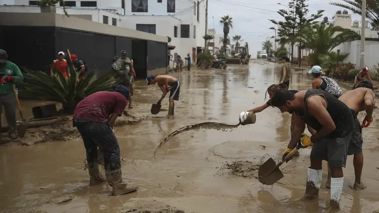 Fotograf&iacute;a de archivo, tomada el pasado 5 de marzo, en la que se registr&oacute; a un grupo de personas al remover el lodo de una calle afectada por las lluvias, tras el paso del cicl&oacute;n Yaku, en el balneario de Punta Hermosa, al sur de Lima (Per&uacute;)./ EFE