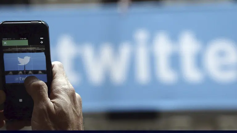 Imagen de archivo de una persona mirando el movil con el logo de Twitter./ EFE