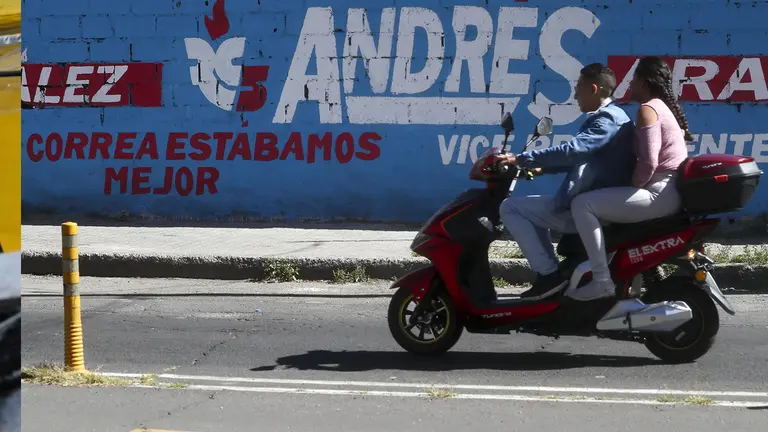 Una pareja en motocicleta pasa frente a una publicidad pol&iacute;tica de la candidata a la presidencia de Ecuador Luisa Gonz&aacute;lez y Andr&eacute;s Arauz como vicepresidente hoy, en Quito (Ecuador)./ EFE