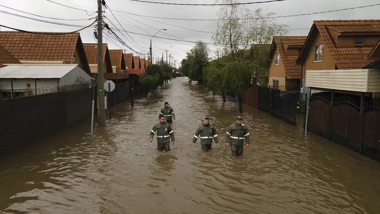 Rescatistas caminan por una calle inundada tras el desborde del r&iacute;o Claro, en la ciudad de Talca (Chile)./ EFE