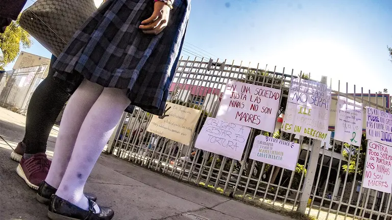Una estudiante observa los carteles que pegaron activistas en las puertas del Hospital Materno Infantil Germán Urquidi en junio de 2022, luego de que le negaran la ILE a una niña víctima de violación./ DICO SOL&Iacute;S