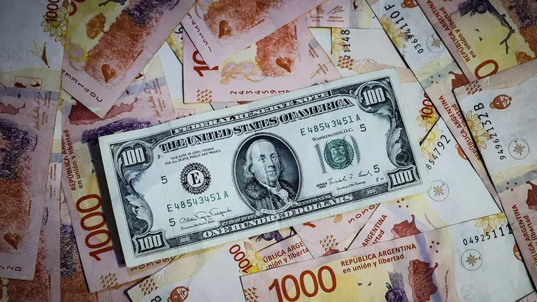 Fotograf&iacute;a comparativa de archivo de billetes de pesos argentinos con un billete de 100 dolares estadounidenses. / EFE