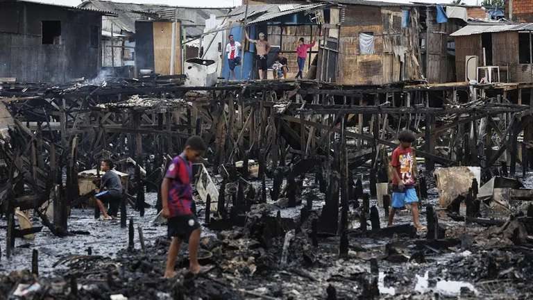 Personas observan los restos y buscan objetos tras un incendio de grandes proporciones que destruy&oacute; m&aacute;s de 100 viviendas de madera construidas sobre palafitas, hoy en Santos (Brasil)./ EFE