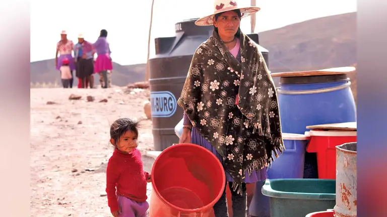 Una mujer espera por agua junto a su hija./ APG