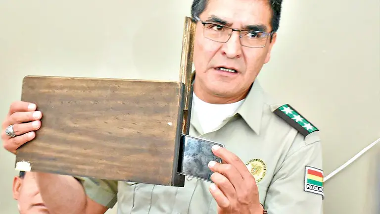 El comandante de la Policía de Cochabamba, Jorge Ríos, muestra  celular oculto en mueble./ DICO SOLÍS