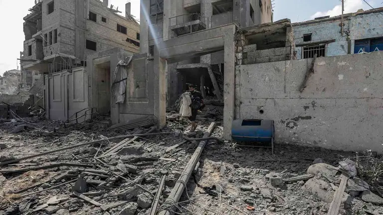 Un palestino fue registrado este martes, 10 de octubre, al carga pertenencias recuperadas, mientras camina entre los escombros de una zona destruida por los ataques a&eacute;reos israel&iacute;es, en el barrio de Al-Ramal, en la ciudad de Gaza. EFE