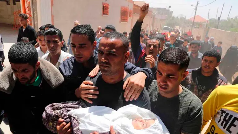 El padre de una ni&ntilde;a muerta por un proyectil la lleva a su funeral, el domingo en Gaza. En v&iacute;deo, alto el fuego entre Israel y milicias de Gaza. FOTO DE ATLAS PUBLICADO EN EL PA&Iacute;S