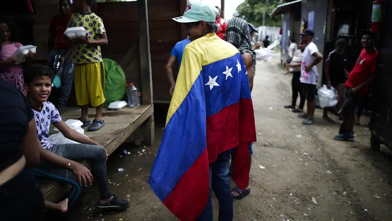 William Maldonado, un migrante venezolano de 22 a&ntilde;os sostiene una bandera de Venezuela en una estaci&oacute;n de recepci&oacute;n migratoria./ EFE