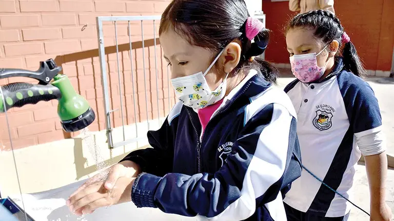 Una escolar se lava las manos en una pileta de su escuela./ NOÉ PORTUGAL
