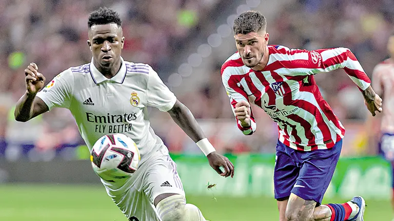 Vinicius Jr. (i) y Rodrigo de Paul (d) pugnan un balón en un clásico madrileño pasado./ DAZN