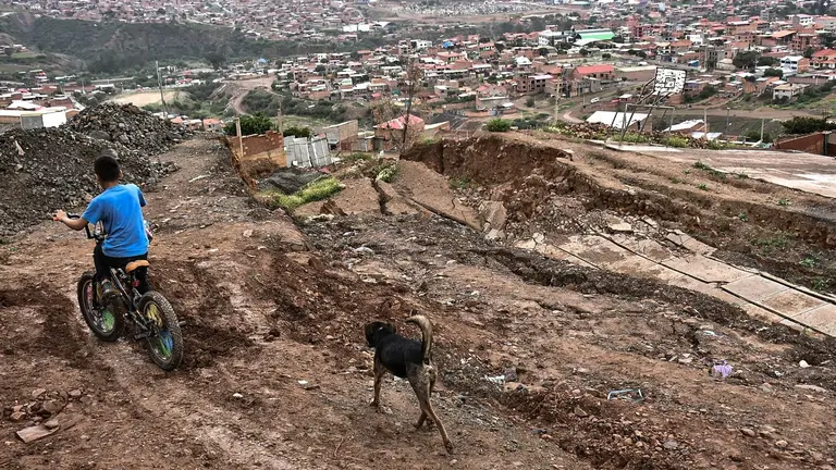 Un ni&ntilde;o circula en una bicicleta por un sector donde antes hab&iacute;a una calle asfaltada en Takoloma. DICO SOL&Iacute;S