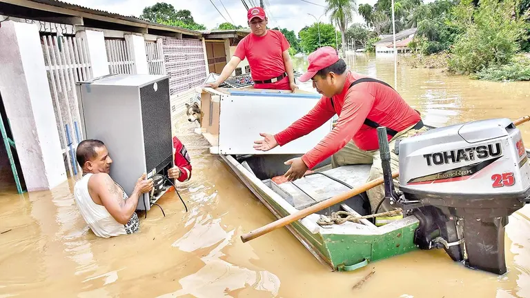 Equipos de rescate ayudan a un vecino a salvar sus bienes, en Cobija./ APG